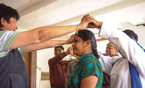 Two women are holding hands around another Indian woman.